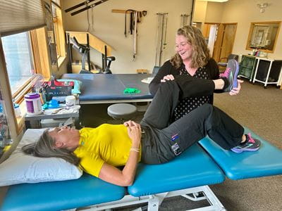 A patients rests on a table while getting her leg stretched