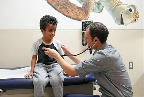 A physician uses a stethoscope to listen to a child's heart