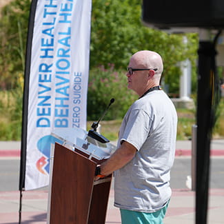 A speaker stands at a podium during a program for Suicide Awareness Prevention Month